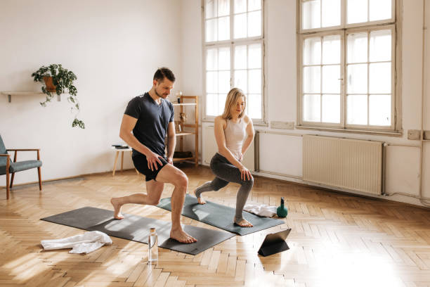 A young couple in San Francisco doing lunges during their home workout routine, staying active and having fun together