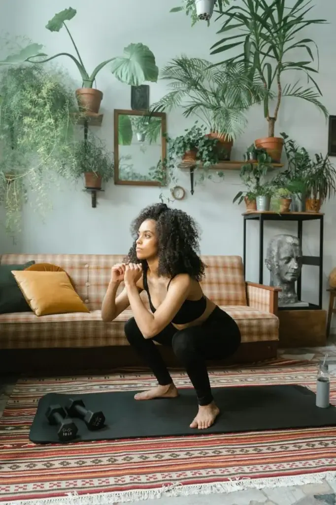 Female beginner performing bodyweight squats at home - strength training without equipment