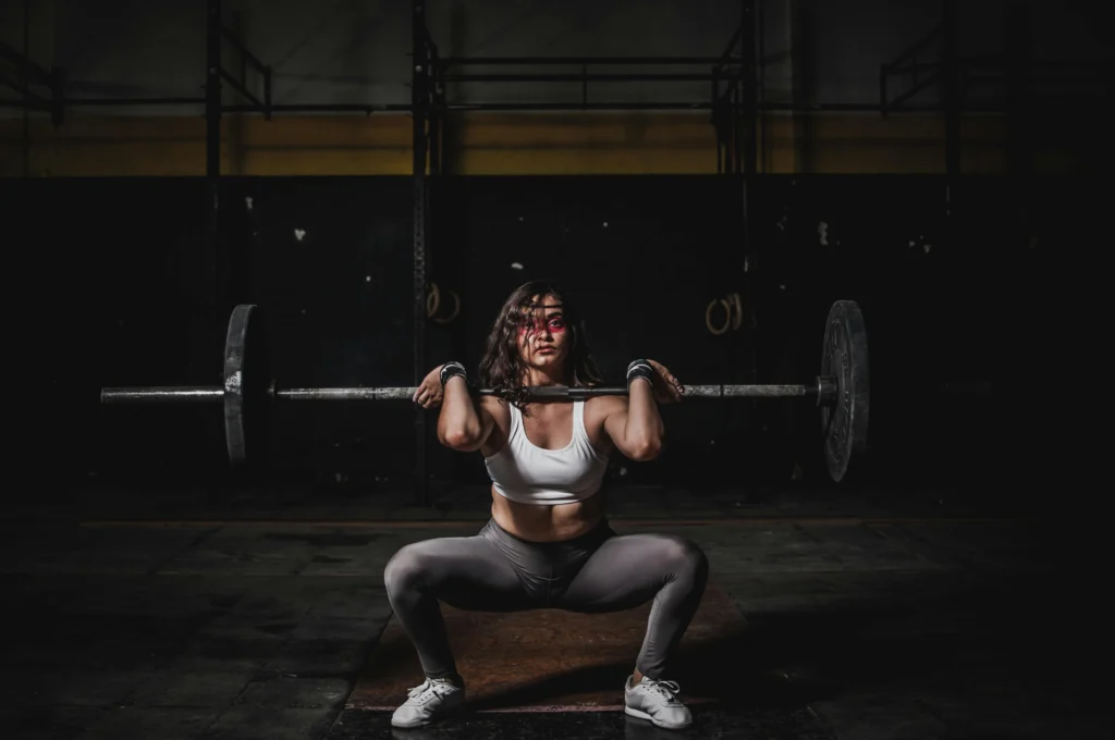 Woman performing squats with a barbell, highlighting lower body strength exercises in a cutting workout.