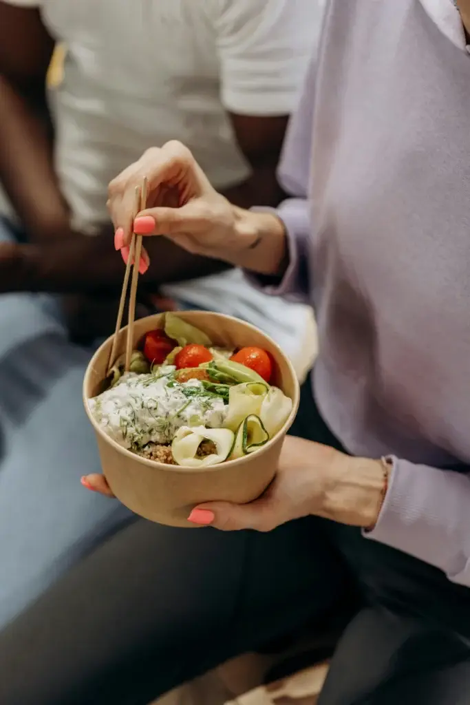 Person holding a healthy salad bowl, emphasizing the importance of balanced nutrition during a cutting phase.