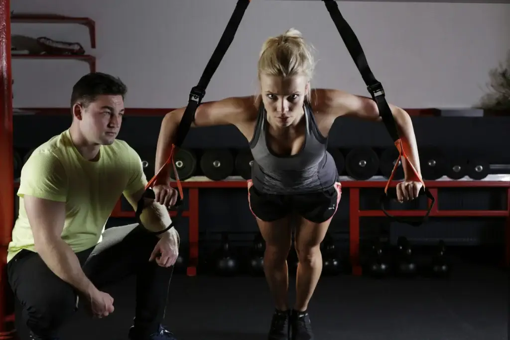 Woman performing suspension training with guidance from a coach, focusing on strength training during a cutting workout in Los Angeles.