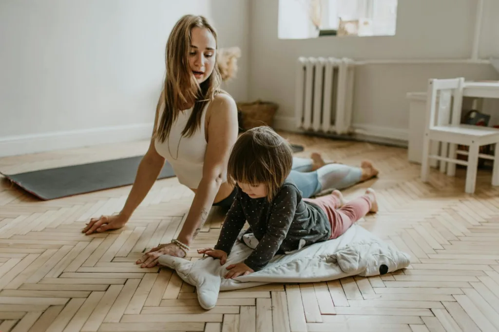 A mother and child practicing the Cat Stretch exercise together at home on a sunny day, promoting wellness, bonding, and daily fitness.