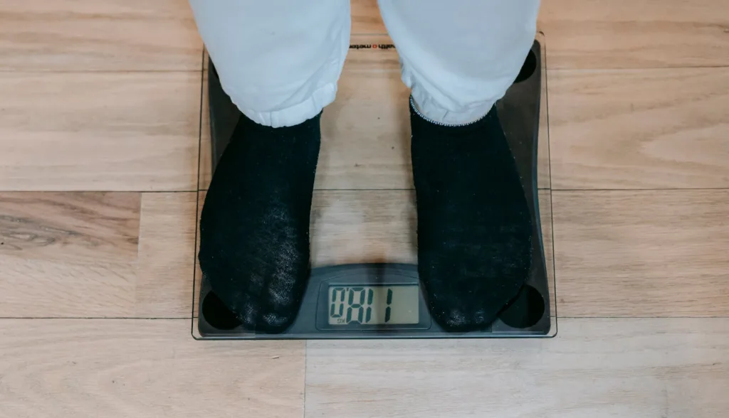 Person standing on a weighing scale to check how many pounds they have lost.