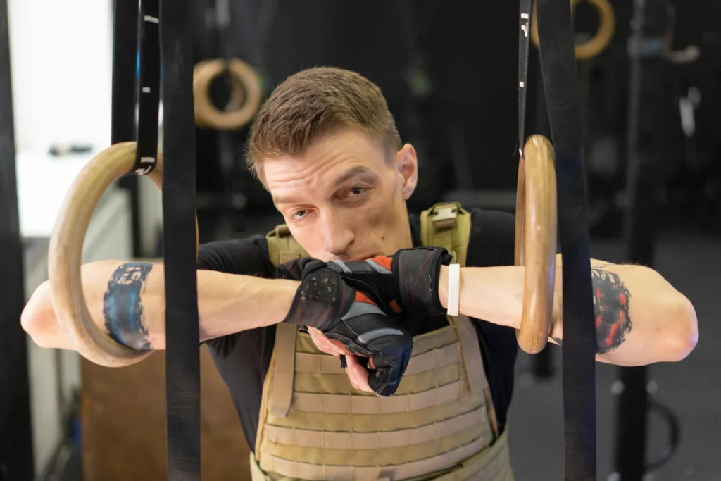 A Man Wearing Workout Gloves Resting his Arms on Gymnastic Rings For HIIT In New York City