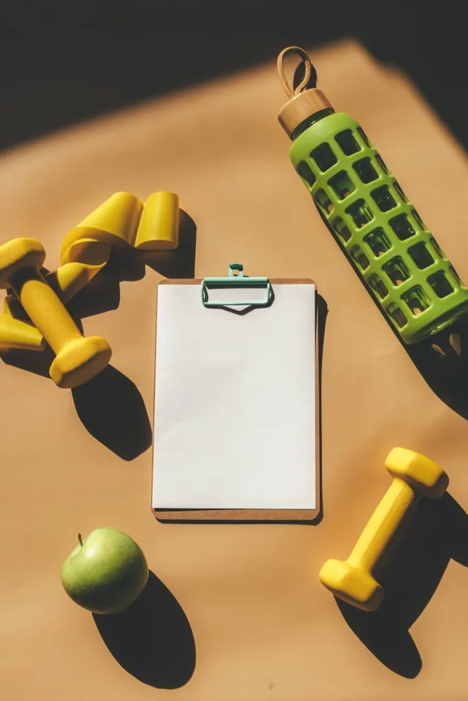 A minimalist flat lay of fitness gear, a clipboard, and an apple.