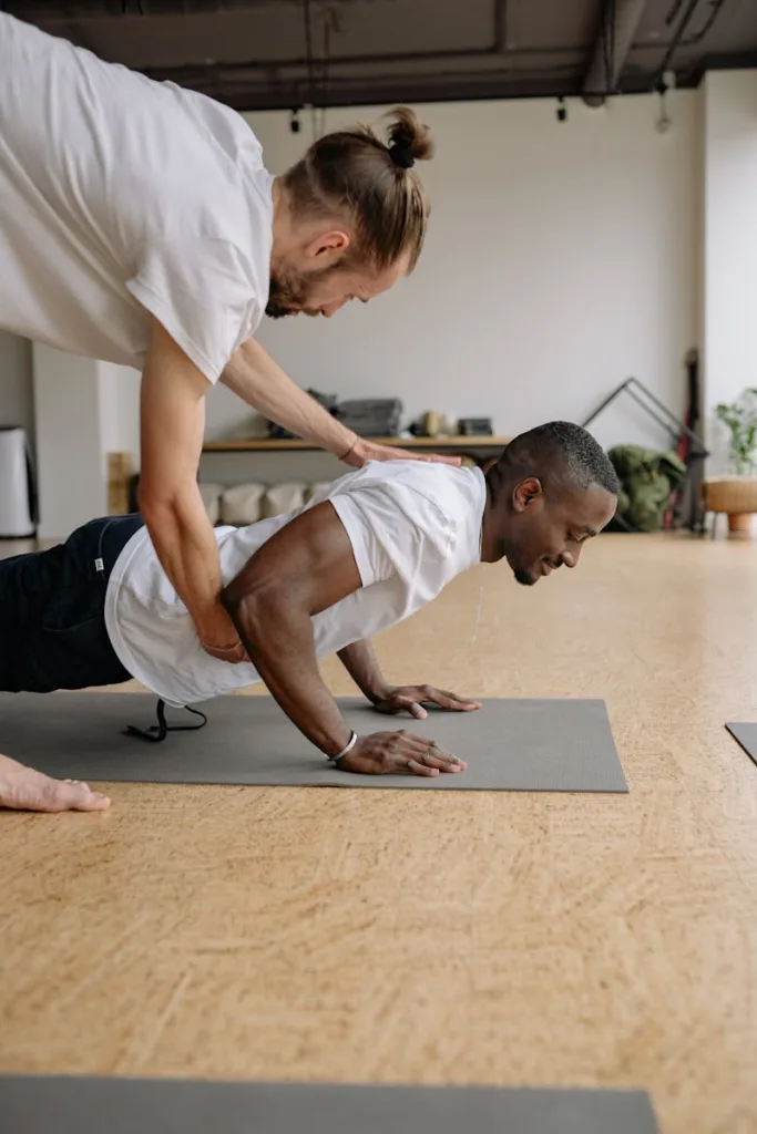 A personal trainer helps a client perform push-ups indoors on gym mats in Chicago