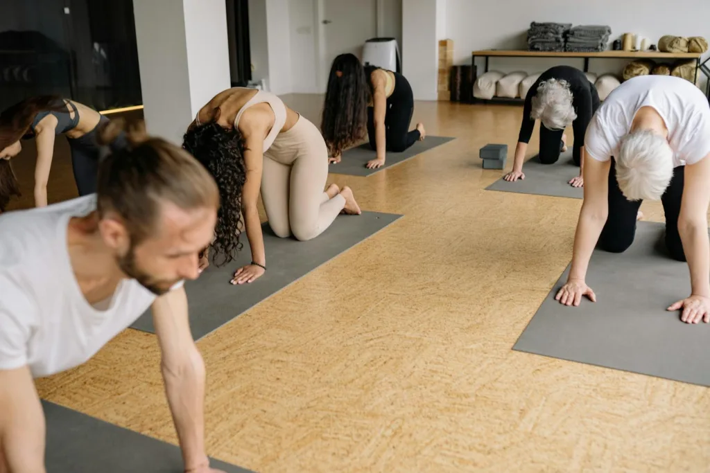 A diverse group practicing the Cow Stretch exercise in a studio during a wellness session, enhancing relaxation, flexibility, and overall well-being.