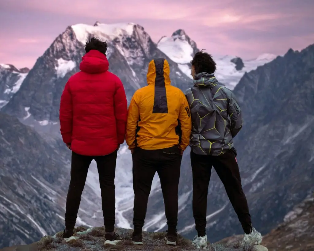 a group of people standing on a mountain top looking at the mountains