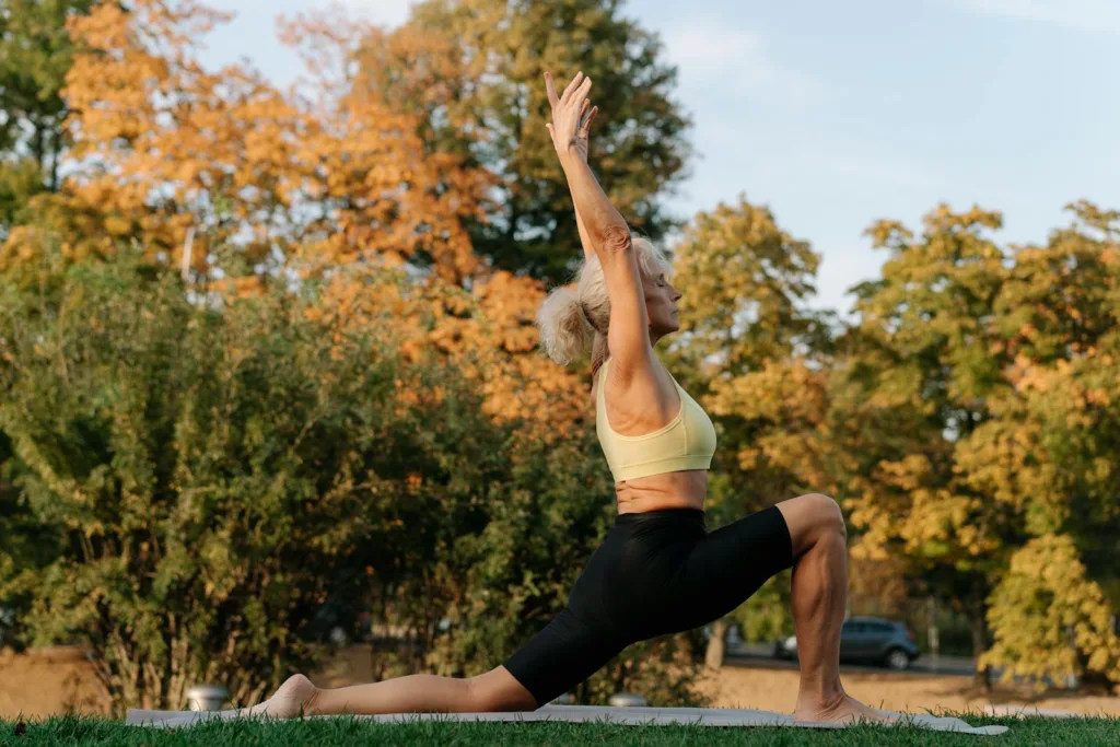 Older adult practicing yoga in the park, highlighting gentle exercises for strength and mobility in an American lifestyle.