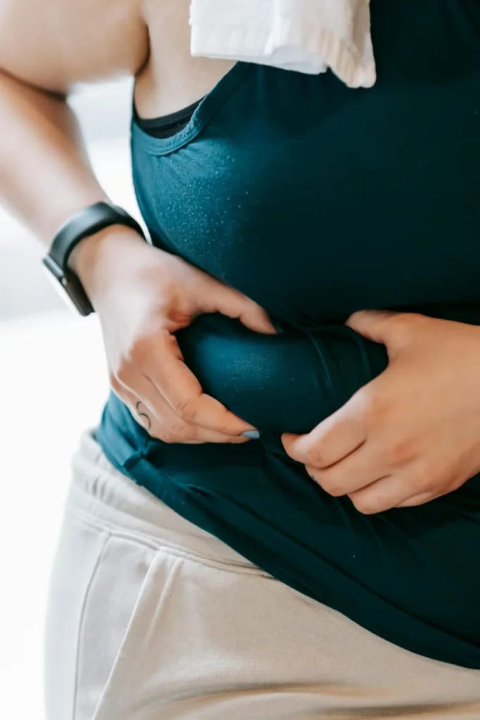 American woman showing her belly fat to motivate others in their journey to lose belly fat