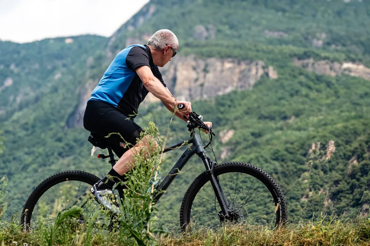 American man cycling through a scenic outdoor trail, embracing fitness and staying active as part of his senior lifestyle.