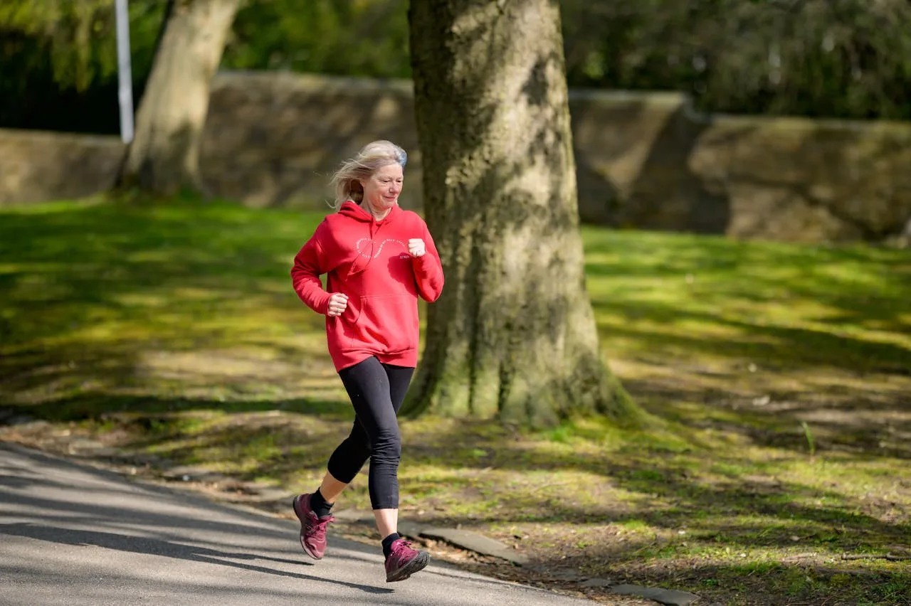 American woman jogging in a park, maintaining her fitness and promoting a healthy, active lifestyle for seniors.