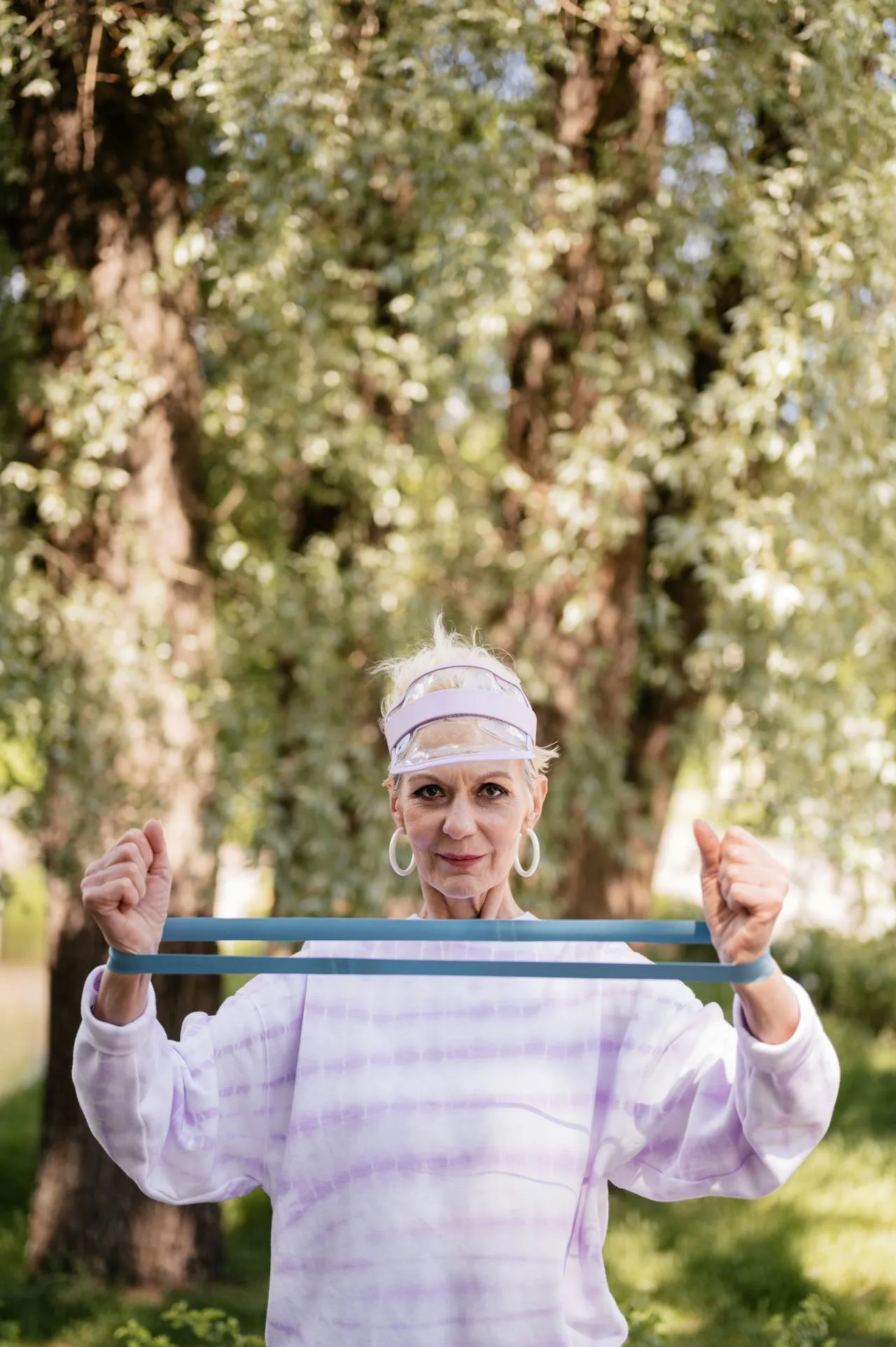 Senior woman performing resistance band exercises outdoors in a park, promoting fitness for Americans with a focus on senior wellness and strength training.