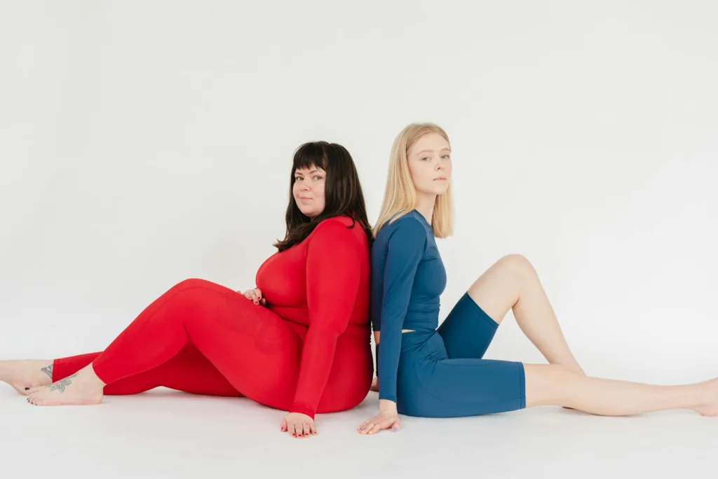 A fit woman sitting beside a plus-sized woman in workout attire, inspiring Americans to support and motivate each other on their weight loss journeys.